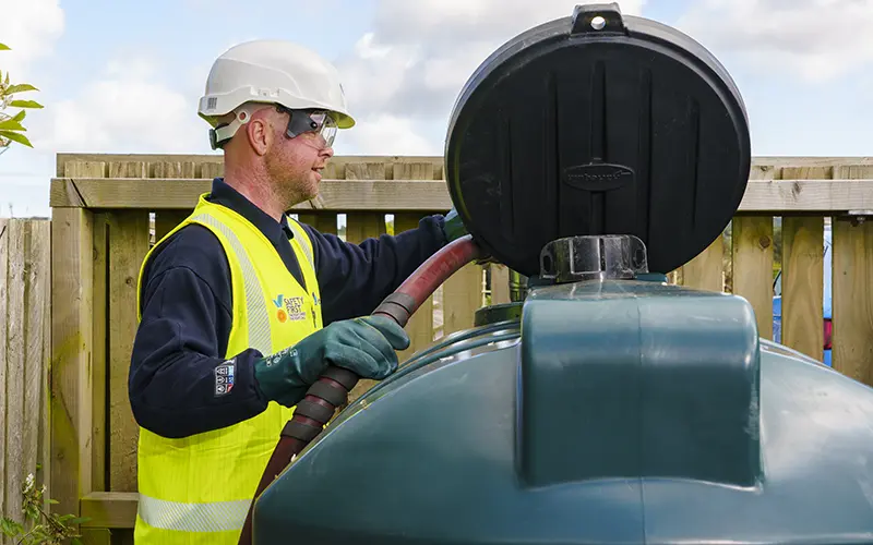 Man filling Certas Energy fuel tank wearing hi-vis vest and hard hat for safety.